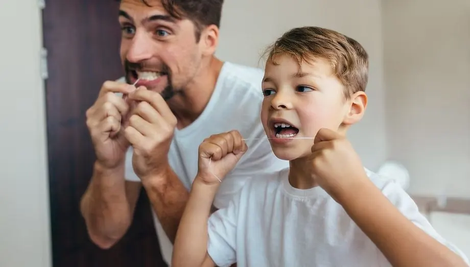 A father and son flossing together: family dental care at VitalDent, Secunda